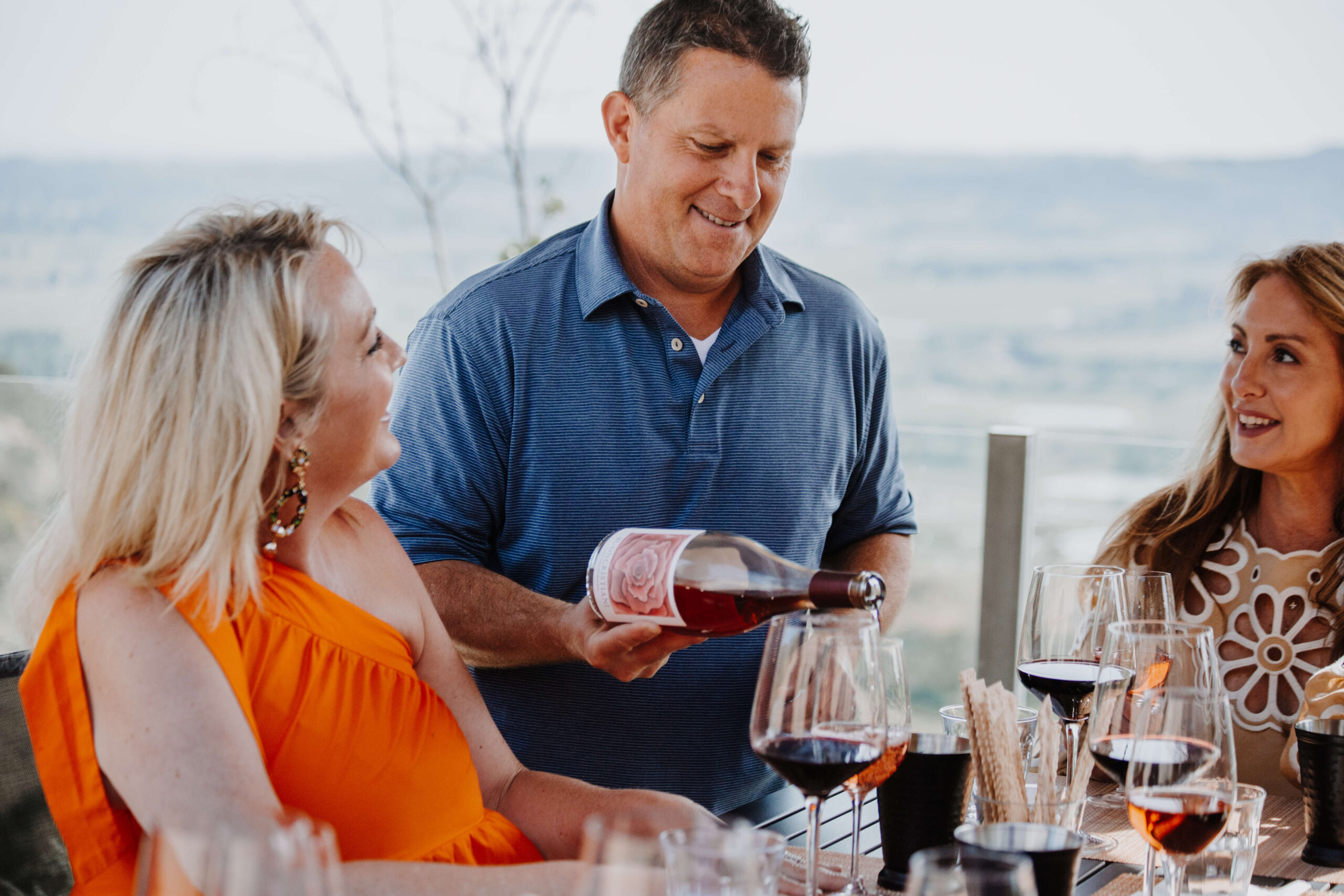 Brother pouring rosé for guests at a private tasting